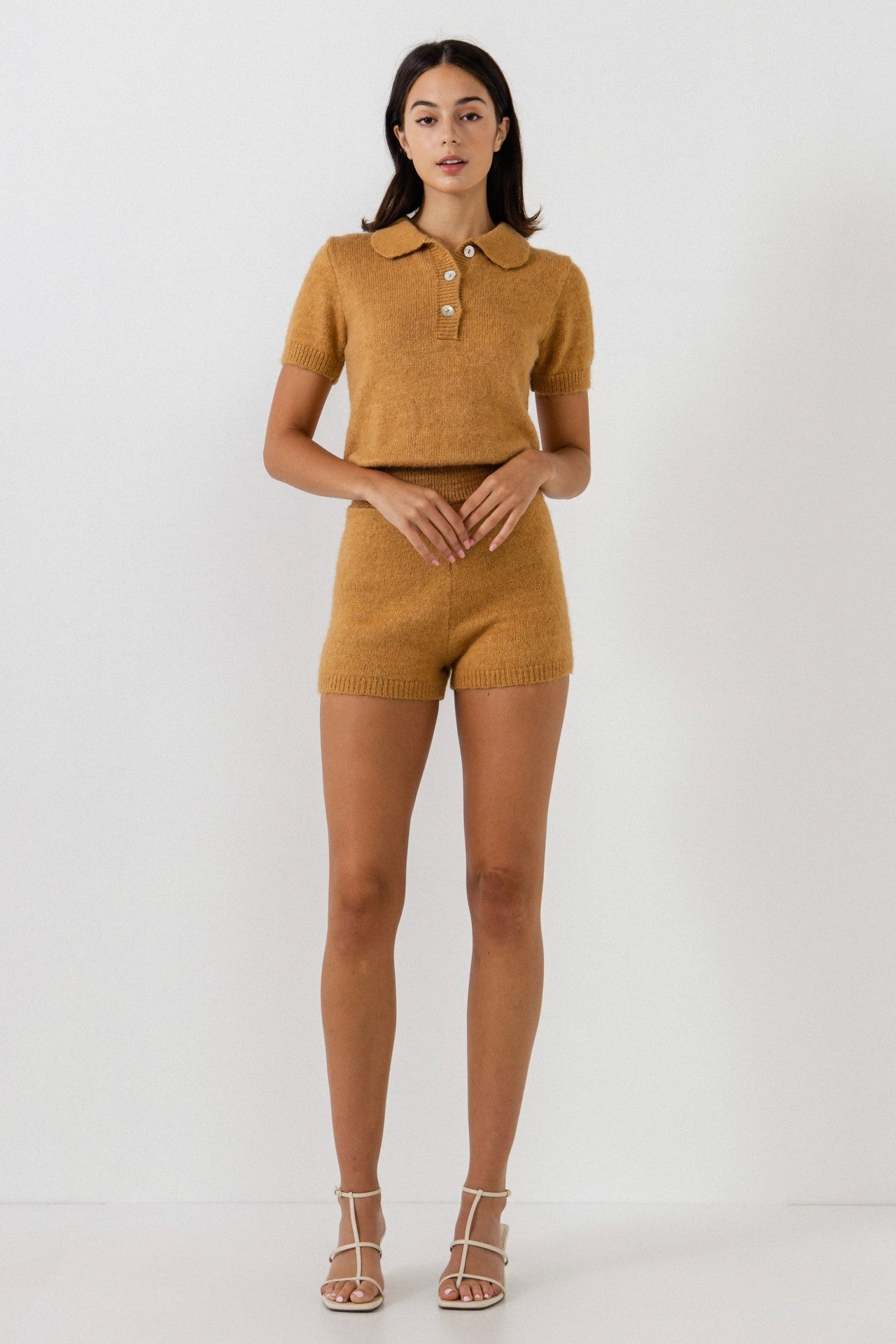 UNIKONCEPT Lifestyle Boutique and Lounge; Model wearing Cozy Chalet Romper in gold by English Factory - a knit romper with short sleeves and polo button collar