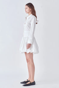 Photo of model wearing Poppy Poplin Button Up Dress in White With bubble skirt, button detailing, and collar available at UniKoncept in Waterloo side view