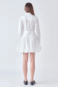 Photo of model wearing Poppy Poplin Button Up Dress in White With bubble skirt, button detailing, and collar available at UniKoncept in Waterloo back view