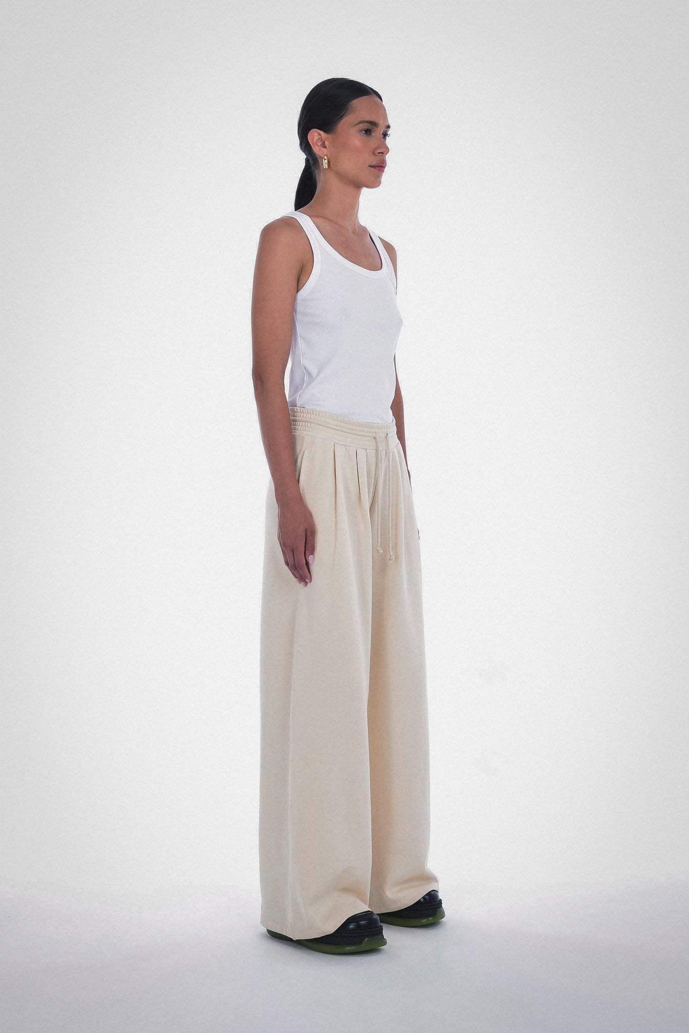 Photo of Model wearing Wen Pleated Pants in an oatmeal colour with pleated wide leg detailing and drawstring from Paper the Label available at UniKoncept in Waterloo - Side View
