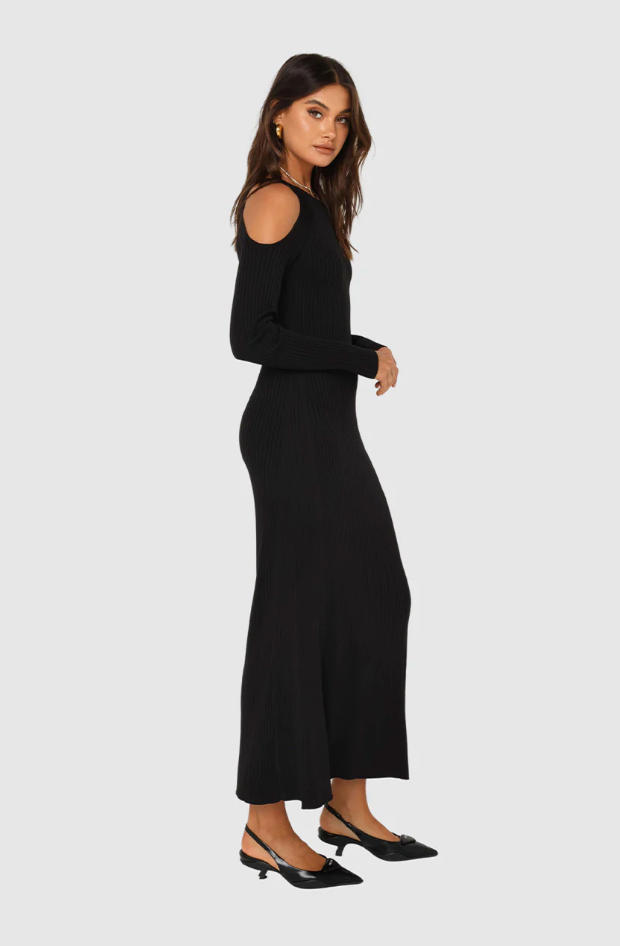 Photo of model wearing evelyn knit dress with a maxi length in the colour black with cut out shoulder details available at UniKoncept in Waterloo side view