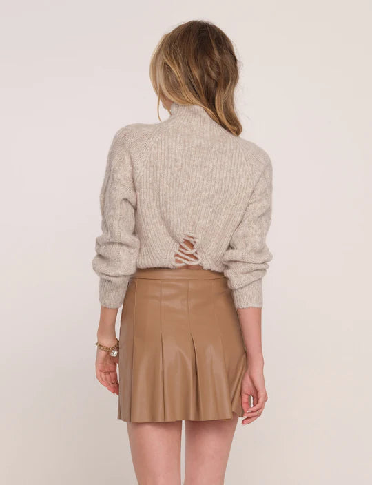 Back view of model wearing Heartloom Ami Skirt in the colour "Desert": A camel-coloured pleated vegan leather a-line skirt. Featured with the Heartloom Thames sweater.