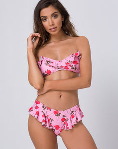 Front view of a model wearing a strapless, bandeaux style, bright pink bikini top with fuchsia flowers and a ruffle trimmed hem. 