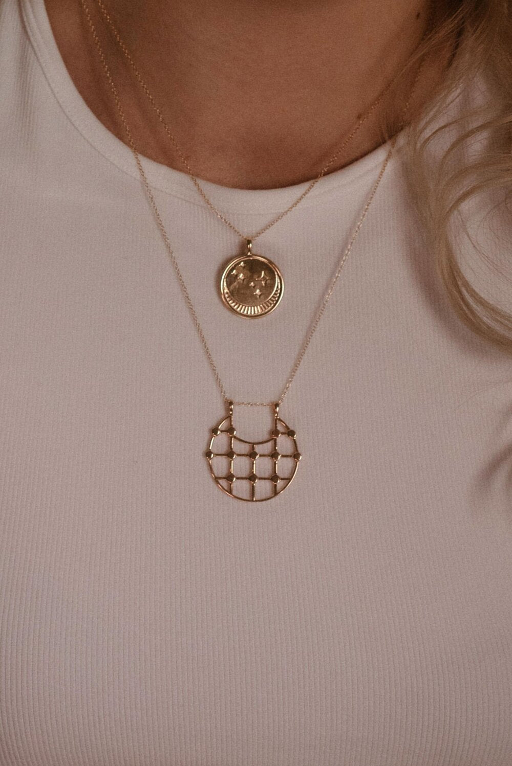 UNIKONCEPT Lifestyle boutique: image shows the Franz Necklace in gold rose quartz by Sarah Mulder. This necklace features a circular pendant engraved with a moon and star details as well as a small rose quartz stone. The pendant hangs from a delicate gold chain.