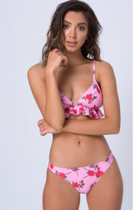 Front view of a model wearing mid-rise bright pink bikini bottoms with a fuchsia flower print.