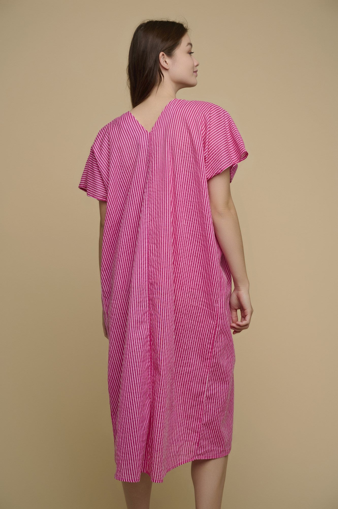 Model is wearing Tuvana Cover Up in pink stripe from rino and pelle back view