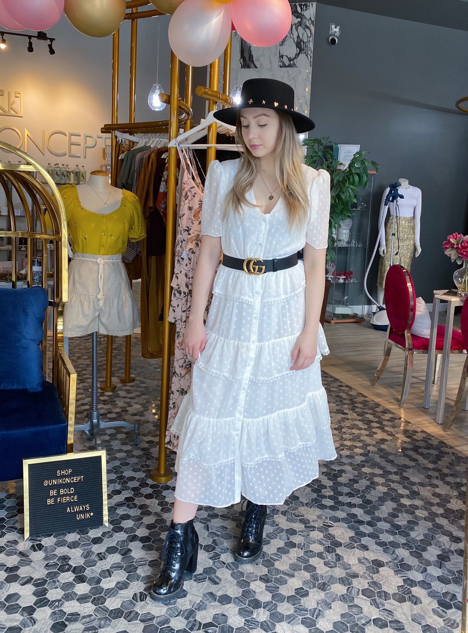 UNIKONCEPT Lifestyle boutique: The image shows the Hamptons White Dress by Free the Roses. This white, ankle length button down dress is extremely elegant with a v-neck and relaxed billowing short sleeves. The fabric is made with small white dots on the white base to add some dimension. The long skirt is tiered and ruffled with a lattice lace detailing as a trim on each layer. 