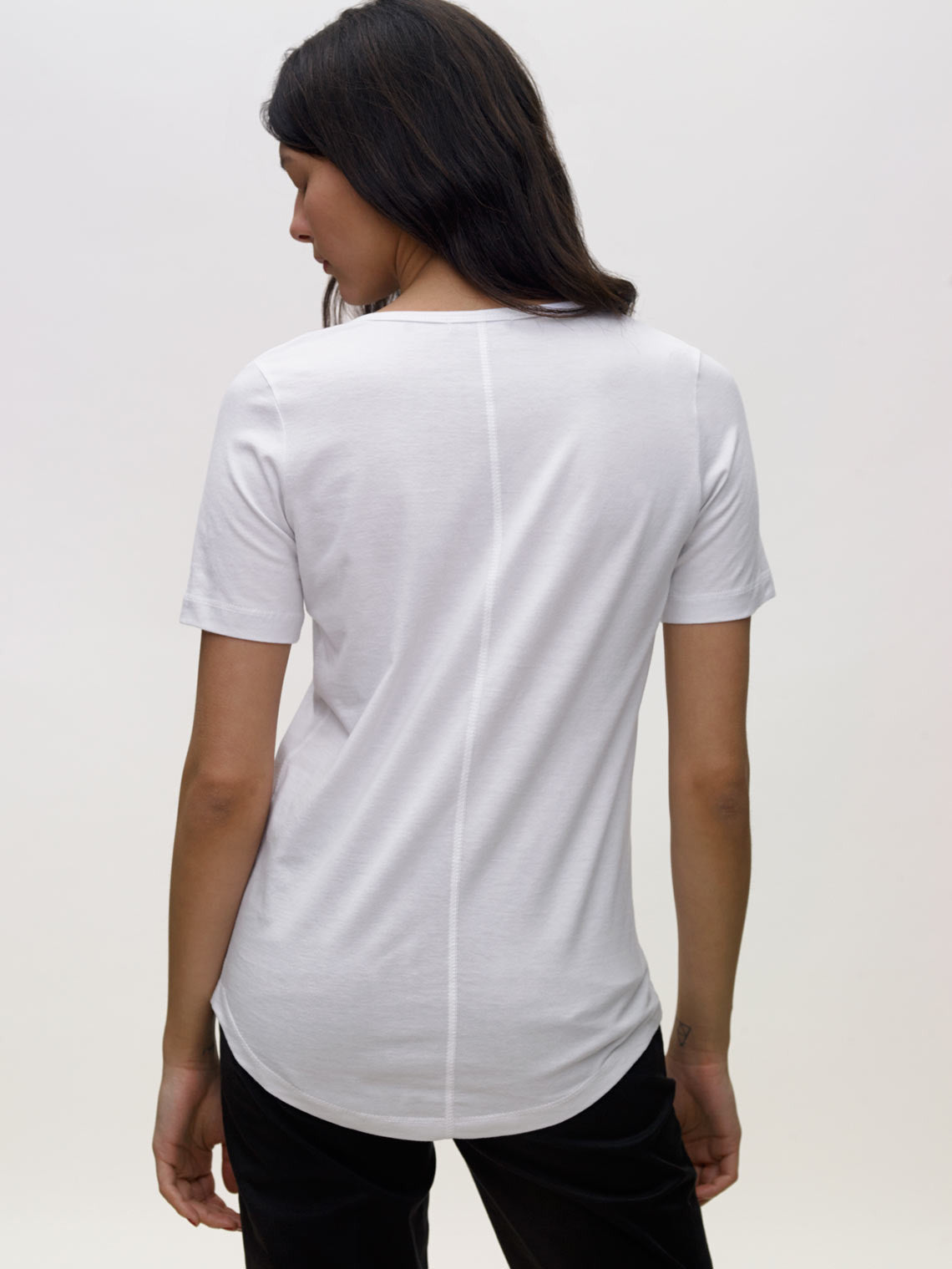 Model wearing white, v neck, KOTN t-shirt. View of Models back.
