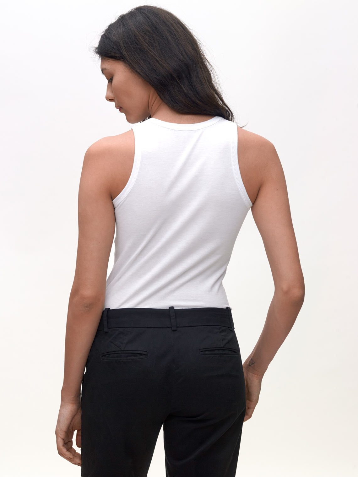 Model wearing White, High neck slim KOTN Tank Top. View of the back.