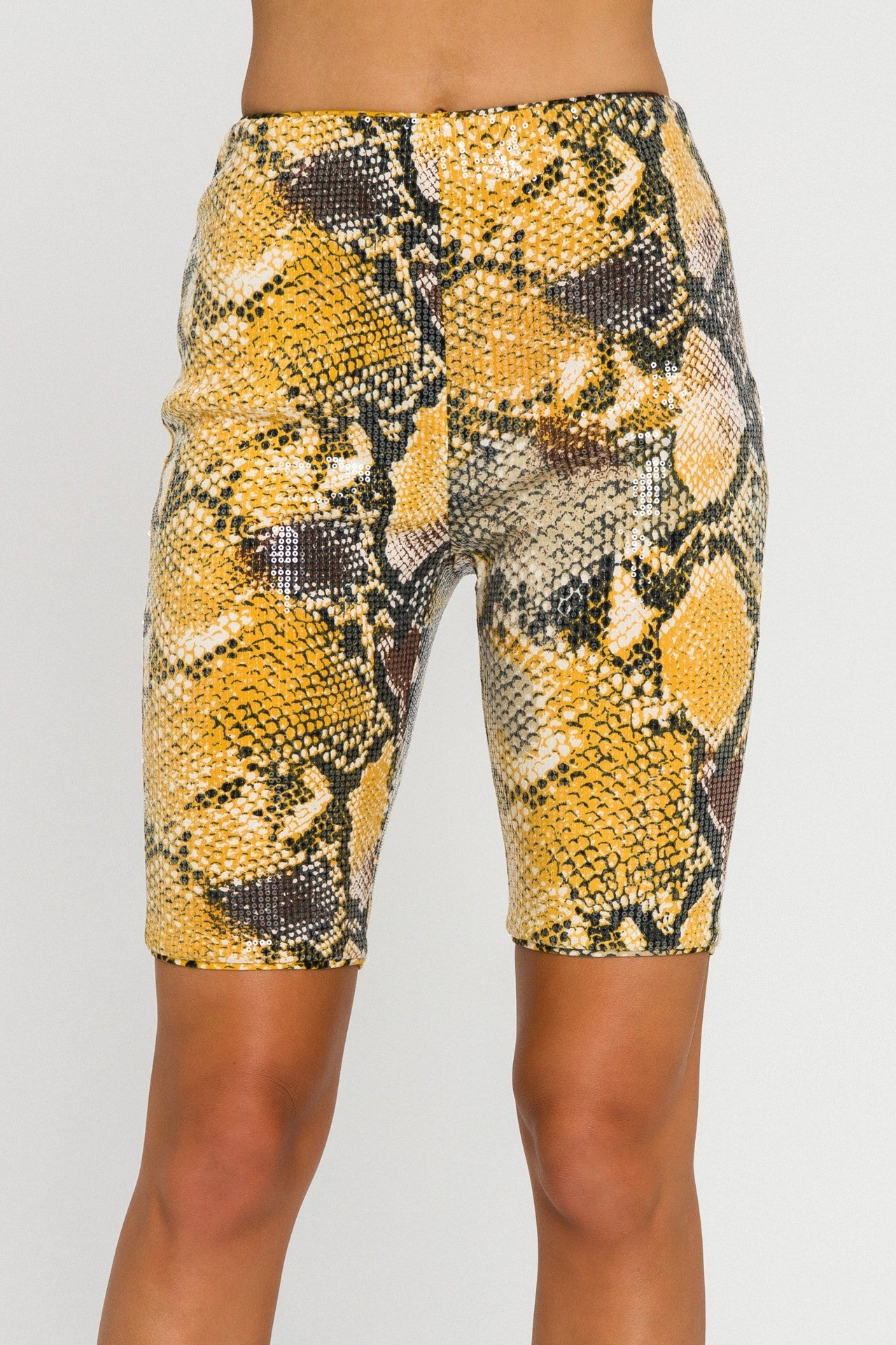 UNIKONCEPT LIFESTYLE BOUTIQUE: This model is wearing the Python Bike shorts by English factory in a black, yellow, brown and cream python snake pattern which is layered with clear sparkly sequin. The shorts are high waisted and feature an invisible zipper on the side seam for an easier fit. They are lined for extra comfort.