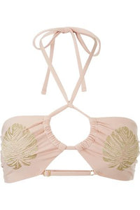 Image shows a Flat lay of a Minkpink nude bikini top, the front of the golden hour ruched halter top features a spaghetti tie halter closure, a key hole with gathering at the centre bust, and two tropical leaves embroidery in gold on the breasts. 